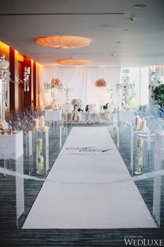 the aisle is decorated with candles, flowers and white linens for an elegant wedding