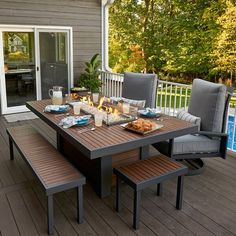 an outdoor table and chairs with a fire pit on the back deck next to a swimming pool