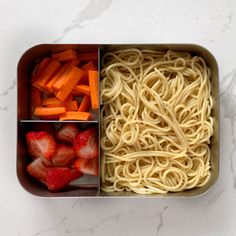 an open lunch box with noodles, strawberries and carrots