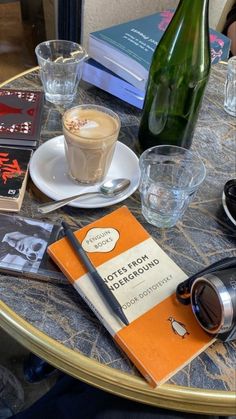 a table topped with books and glasses next to a bottle