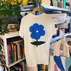 The Studio Tee is a limited edition item and has been created for your everyday adventures. A comfortable unisex fit and made from super soft, GOTS Certified Organic Cotton. You will want to wear it every day! Featured on the left chest is an embroidered Flower Friend. The same joyful flower friend is also shinning big and bright on the back. They're both proudly positioned to shoot positivity to everyone around you. This is the first tee that I've released and I'm excited to be using my artwork Screen Printed T Shirts, Printed Tshirt Designs, Spring Graphic Tee Hand Printed, Summer Graphic Tee With Flower Design, Flower Graphic Tee Design, Blue Floral Print Graphic Tee, Playful Spring T-shirt With All Over Print, Tee Illustration, Flower Graphic Tee