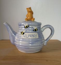 a ceramic teapot with a bear sitting on top of it that says hummy