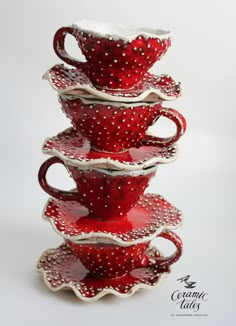 four red cups and saucers stacked on top of each other with white polka dots