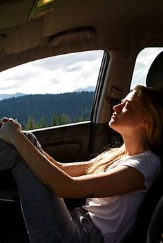 a woman sitting in the back seat of a car with her feet up on the floor