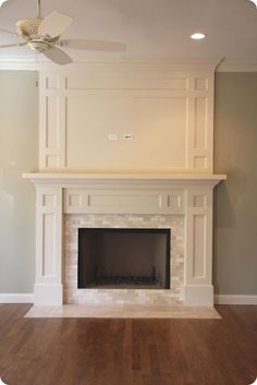 an empty living room with a fireplace and ceiling fan