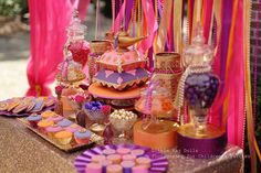 a table topped with lots of candy and candies next to pink draping