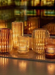 candles are lined up on the window sill in front of a cityscape