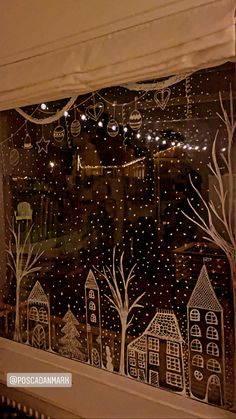 the window is decorated with christmas lights and houses