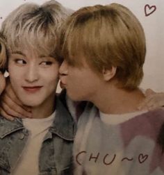 two young men standing next to each other in front of a sign that says love