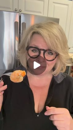 a woman with glasses holding an orange in front of her face