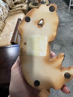 a person holding up a piece of wood that looks like a dog with holes in it