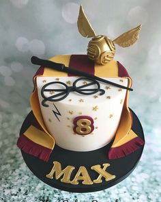 a harry potter birthday cake with glasses, wand and hat on it's top