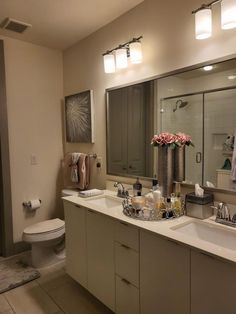 a bathroom with two sinks, a toilet and a large mirror over the bathtub