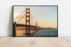 the golden gate bridge in san francisco, california is framed on a wall above a wooden floor