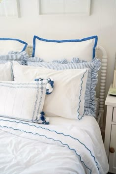 a white bed with blue trimmings and two pillows on it's headboard