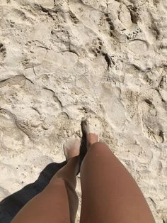 a woman's legs and feet in the sand