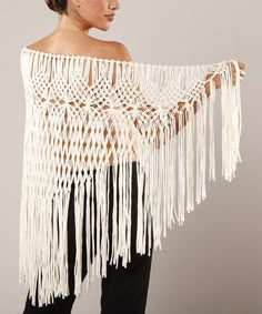 a woman wearing a white crochet shawl with fringes on the sides