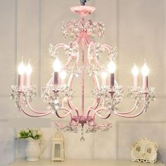 a pink chandelier hanging from the ceiling in a room with white walls and furniture