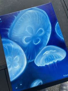 a painting of jellyfish in blue and white on a black surface with a person standing next to it