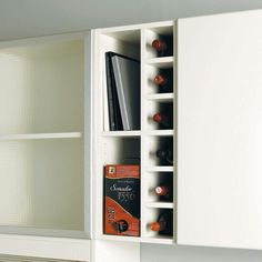 a white cabinet with some books and other items in it's compartments on the wall