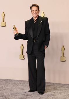 a man in a black suit holding an award for his role in the film,