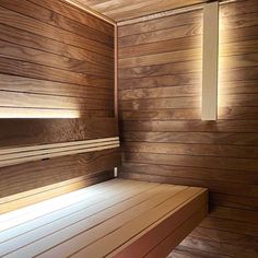 an empty wooden bench in a room with wood paneling on the walls and floor