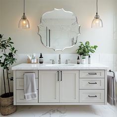 a bathroom with two sinks and a large round mirror above the sink is surrounded by potted plants