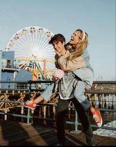 a man carrying a woman on his back in front of a ferris wheel