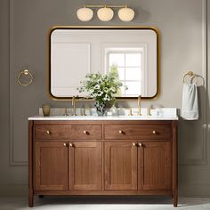 a bathroom vanity with two sinks and a gold framed mirror above it on the wall