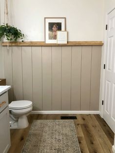 a white toilet sitting in a bathroom next to a wooden shelf above a sink and mirror