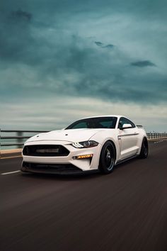 a white ford mustang driving down the road