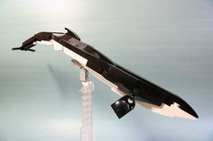 a lego model of a black and white plane on a clear stand with an antenna attached to it