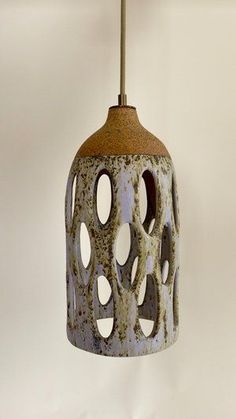 an old, rusty light fixture hanging from a hook on a white wall with holes in it