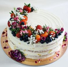 a cake decorated with fresh fruit and flowers on a gold platter for an anniversary celebration