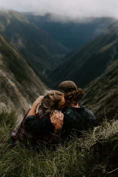 two people are hugging in the mountains