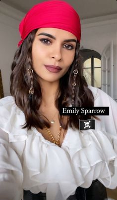 a woman with long hair wearing a red bandana and gold earrings is looking at the camera