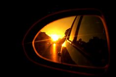 the sun is setting in the side view mirror