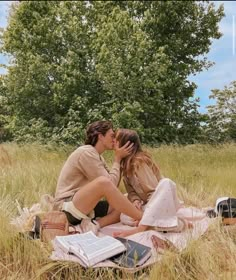 two people sitting in the grass kissing each other