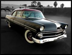 an old black and white car parked in a parking lot