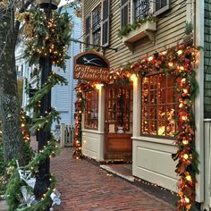 christmas lights adorn the outside of a storefront on a brick sidewalk in front of a building