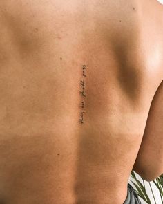 the back of a man with a tattoo on his left side and words written in cursive ink