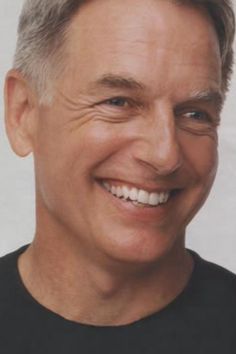 a close up of a person wearing a black shirt and smiling at the camera with a smile on his face