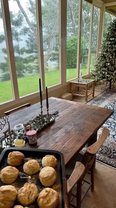 a wooden table topped with muffins next to a christmas tree