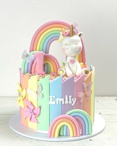 a cake decorated with rainbows, butterflies and a unicorn figurine on top