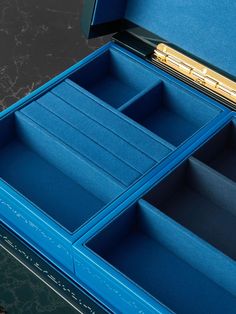 an open blue box with two compartments and a gold bar in the top section, on a marble surface