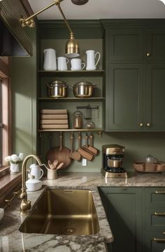 a kitchen with green cabinets and marble counter tops, gold faucets and brass accessories