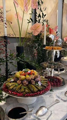 a table topped with lots of food next to tall vases filled with flowers and candles