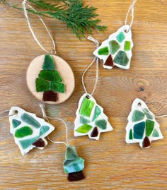 three pieces of sea glass are hanging on a wooden table next to a pine tree