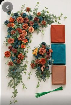 an arrangement of flowers and cloths laid out on a white surface with green leaves