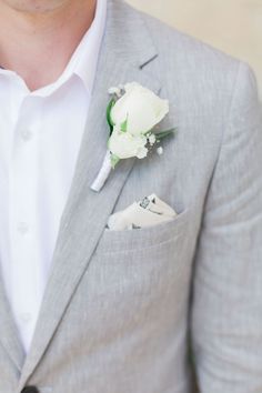 a man in a gray suit with a boutonniere on his lapel